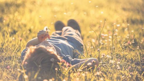 baby-lying-on-the-field-with-dandelion-in-hand